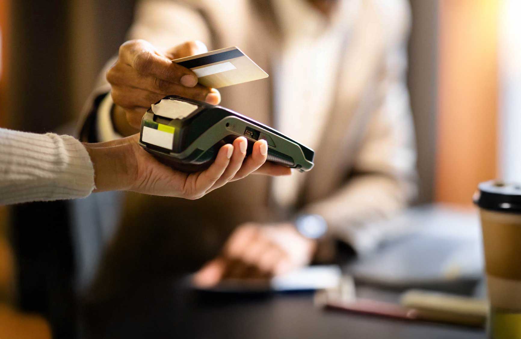 Customer tapping a credit card on a handheld payment terminal.