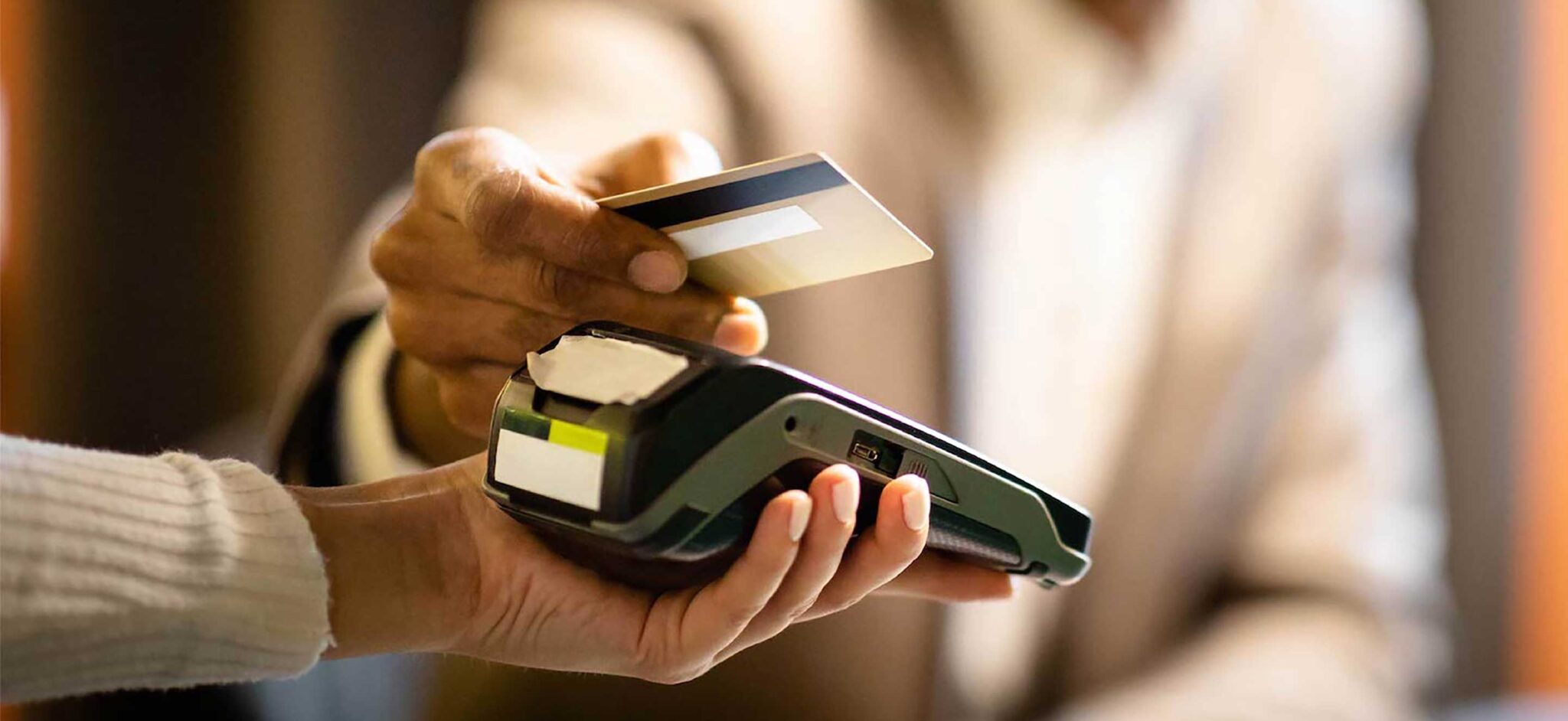 Customer tapping a credit card on a handheld payment terminal.