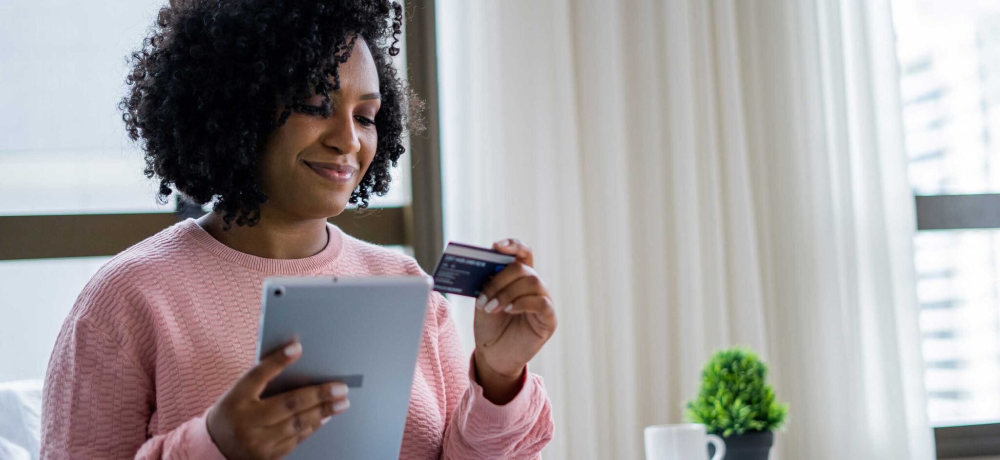 Woman holding a credit card and using a tablet for an online payment.