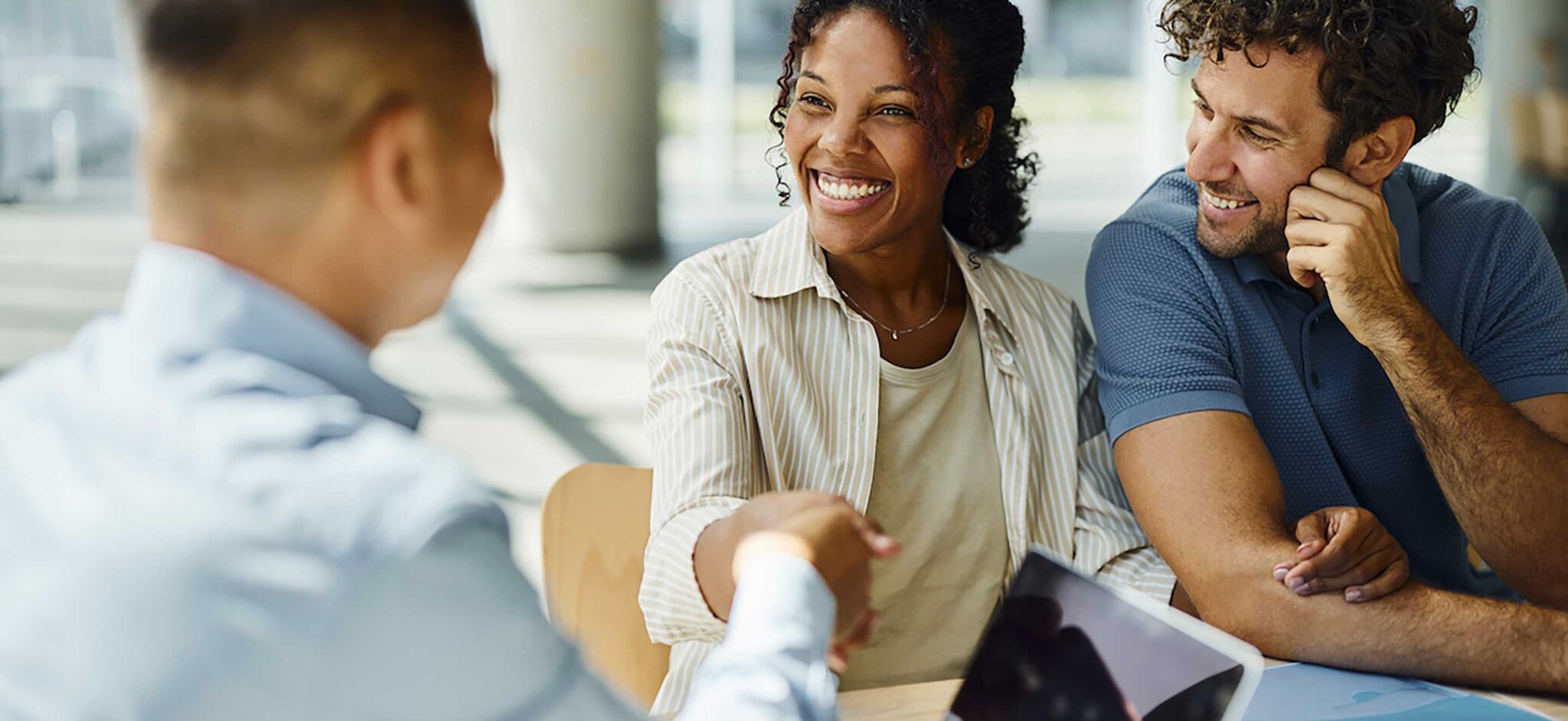 Smiling colleagues in a friendly meeting, engaging with each other across a table.