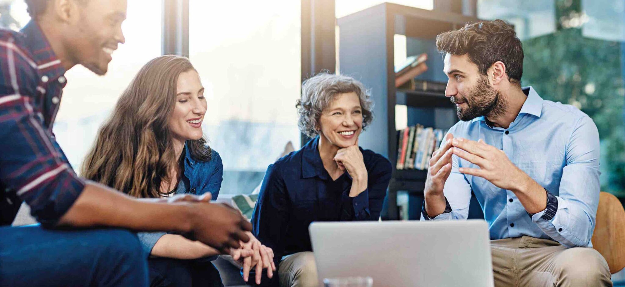 Diverse group of colleagues having a collaborative discussion around a laptop.